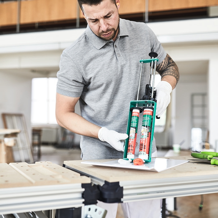 Ein Repair Care Anwender dosiert DRY FLEX® 1 mit einer doppelten Kartuschenpresse auf ein Mischbrett.