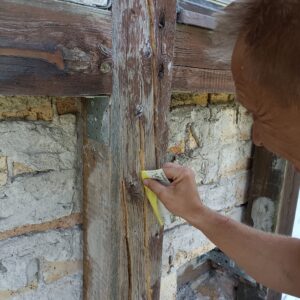 Die ausgefrästen Risse in den Balken eines Fachwerkhauses werden glatt geschliffen, um eine optimale Haftfläche für die folgende Reparatur mit 2K Holzspachtel zu schaffen. Eine saubere Vorbereitung ist entscheidend für eine dauerhafte Ausbesserung.
