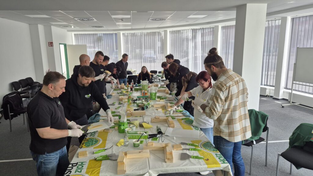 Professionelle Handwerker nehmen an einem Repair Care Seminar teil, in dem sie lernen, dauerhafte Holzreparaturen fachgerecht durchzuführen; sie arbeiten konzentriert an Holzbauteilen, um Reparaturtechniken praktisch zu üben.